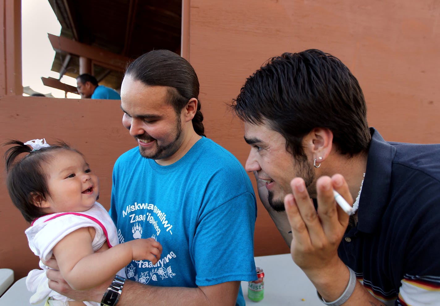 Sam Strong, director of economic development at the Red Lake Indian reservation, holds his niece Sarah, as Justin Beaulieu, the tribe's constitutional reform coordinator, plays along during a feast last week in Ponemah, Minn., Red Lake has just begun exploring whether to re-write its constitution to both better reflect tribal tradition and modern government. (ANNA REED/STAR TRIBUNE) anna.reed@startribune.com (cq)