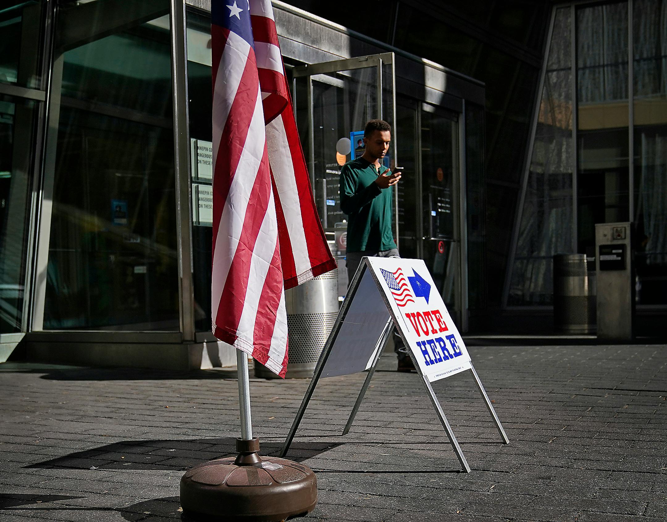 A man walks by a voting sign at the Minneapolis Central Library during the primary election that includes the 5th congressional district in Minneapolis.