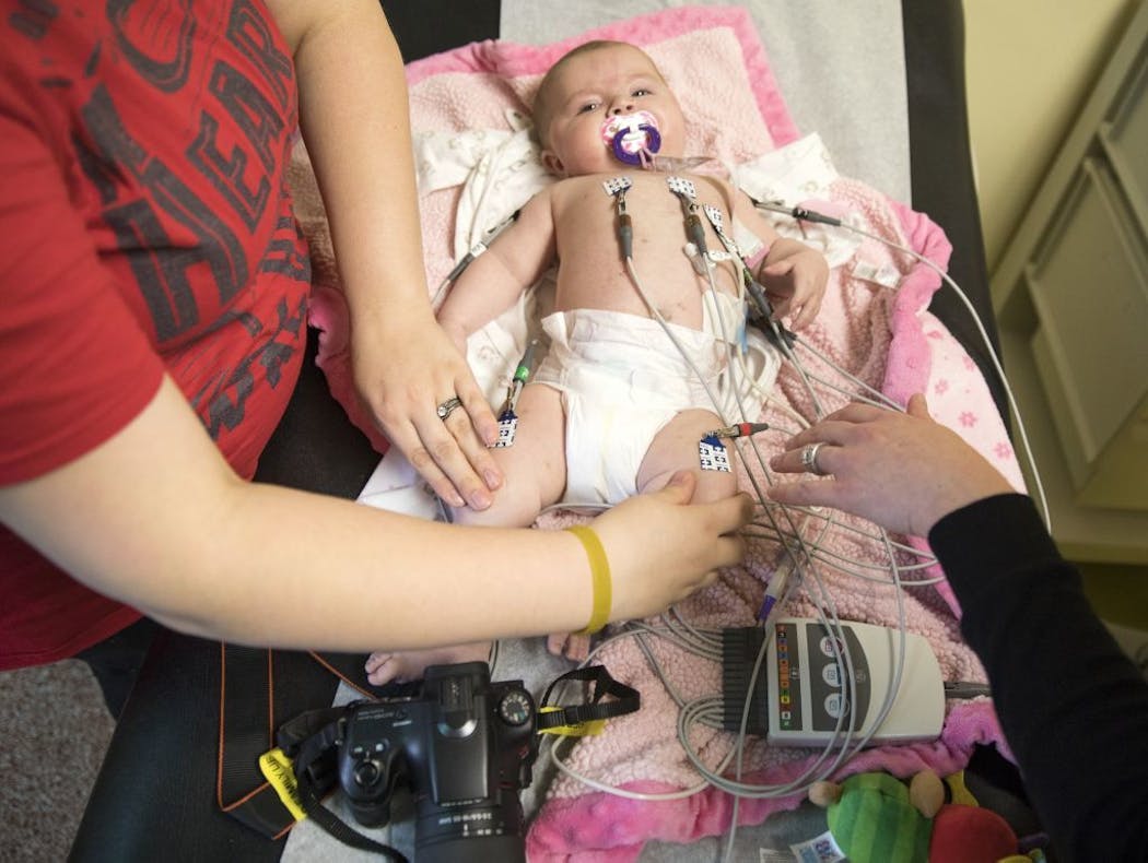 Chelsea Ohlquist put down the camera to help hold her daughter Corah during an electrocardiogram.