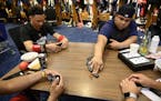 Infielder Ronald Torreyes and catcher Willians Astudillo are among a foursome playing dominoes in the clubhouse before the start of a game against the