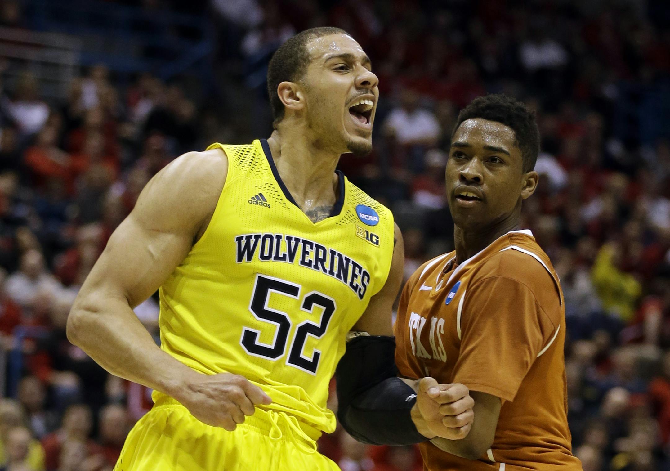 Michigan forward Jordan Morgan (52) reacts to a foul call as Texas guard Isaiah Taylor watches him during the second half of a third-round game of the NCAA college basketball tournament Saturday, March 22, 2014, in Milwaukee. (AP Photo/Jeffrey Phelps)