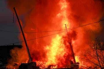 A ball of flame erupts after part of the remains of the Globe Elevators collapses at 2 Banks Avenue after catching fire Monday afternoon in Superior. 