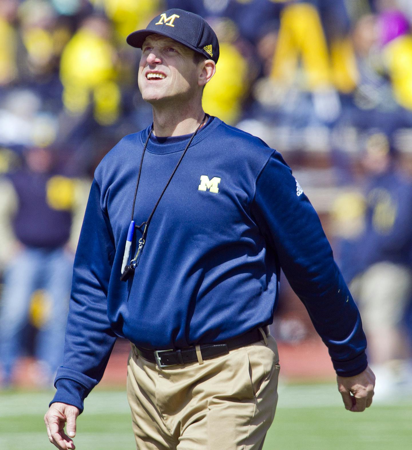 FILE - In this April 4, 2015, file photo, Michigan head coach Jim Harbaugh walks the field between downs during the NCAA college football team's spring game in Ann Arbor, Mich. Now Harbaugh will finally begin coaching the Wolverines in some actual games _ but no matter how this first season in Ann Arbor goes, the quirky, khaki-wearing coach has unified a fractured Michigan fan base. (AP Photo/Tony Ding, File)