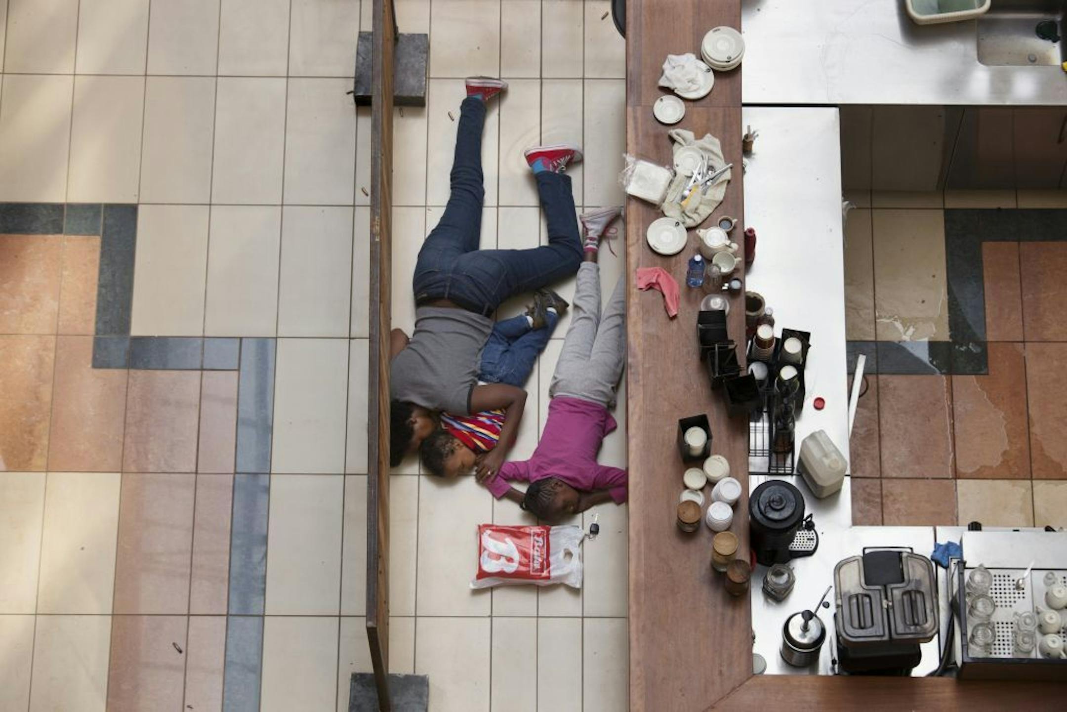 A woman and children hide inside Westgate Mall in Nairobi, Kenya, Sept. 21, 2013. A group of armed men attacked the upscale shopping mall in Nairobi on Saturday, killing at least 59 people and wounding at least 175. On Sunday, extremists holding an unknown number of hostages continued a siege after Kenyan security forces surrounded the facility.