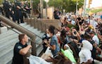 In this file photo, three police officers take a knee with the protesters. Protesters rally outside of the Austin Police Dept Headquarters in Austin, 