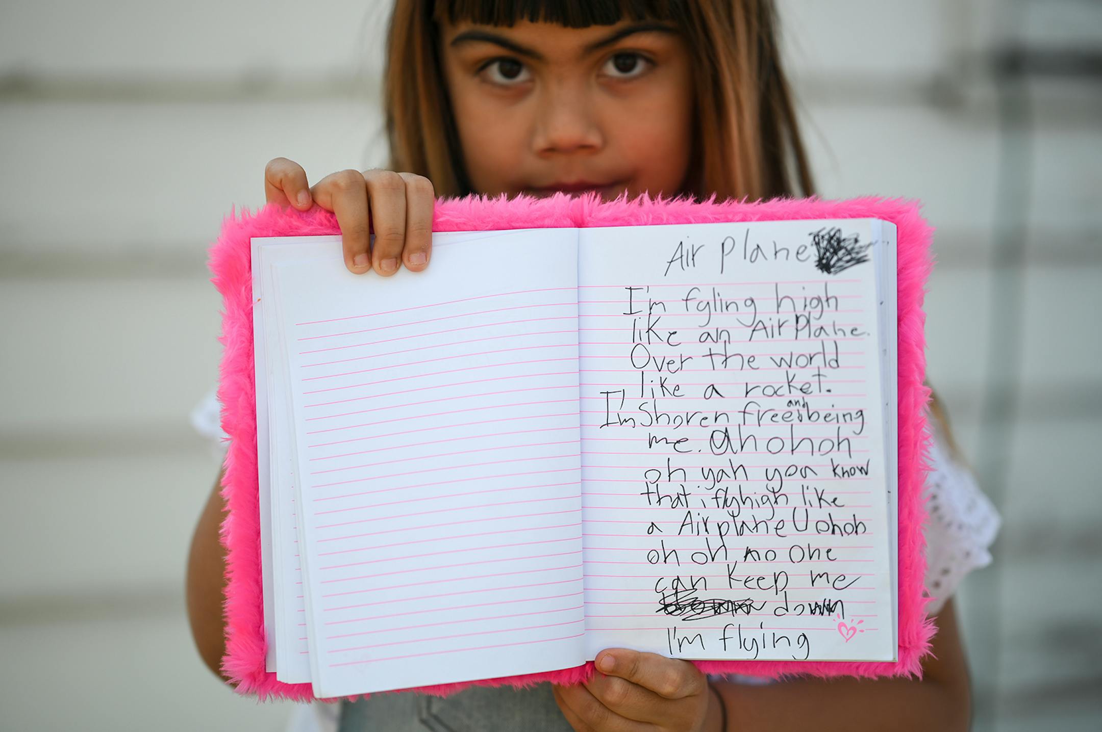 Adella Jonson, 9, held up a song she wrote, titled "Airplane," in her backyard Thursday.