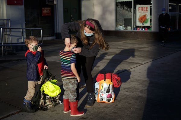 FILE -- Kristy Etheridge adjusts the face masks on her son Noah, 4, left, and friend Ollie Hallock, 5, in Brooklyn on Nov. 13, 2020. Parents in New Yo