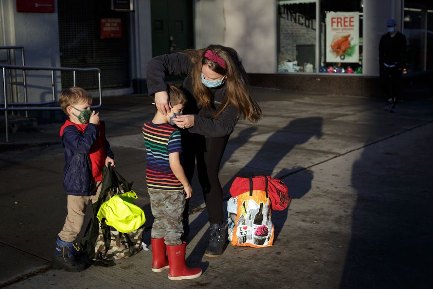 FILE -- Kristy Etheridge adjusts the face masks on her son Noah, 4, left, and friend Ollie Hallock, 5, in Brooklyn on Nov. 13, 2020. Parents in New York have pleaded with Governor Andrew Cuomo to overrule the mayor and keep schools open.