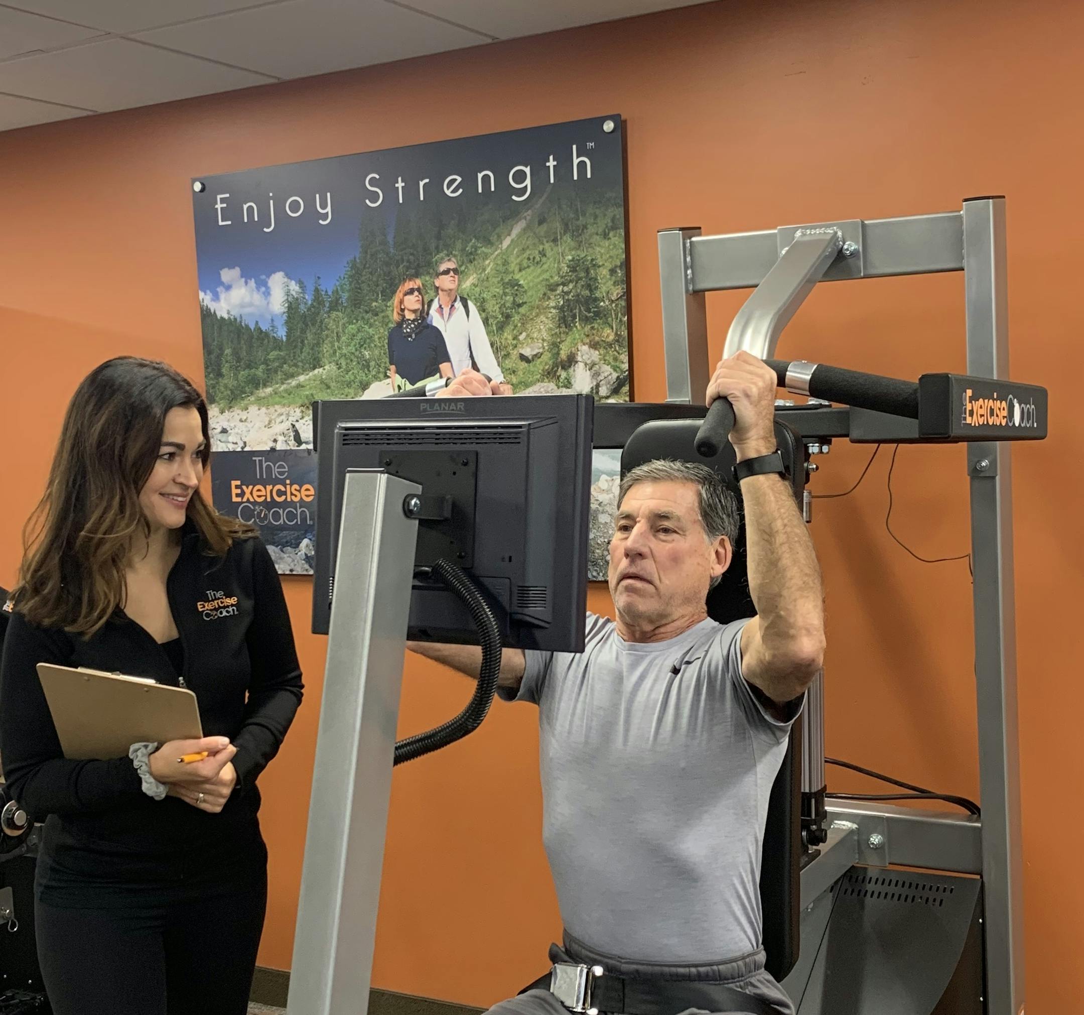 Amy Hudson, who with her husband opened up a second Exercise Coach location in October, works with customer Bruce Johnson on a high-tech smart fitness machine. (Provided by Exercise Coach)