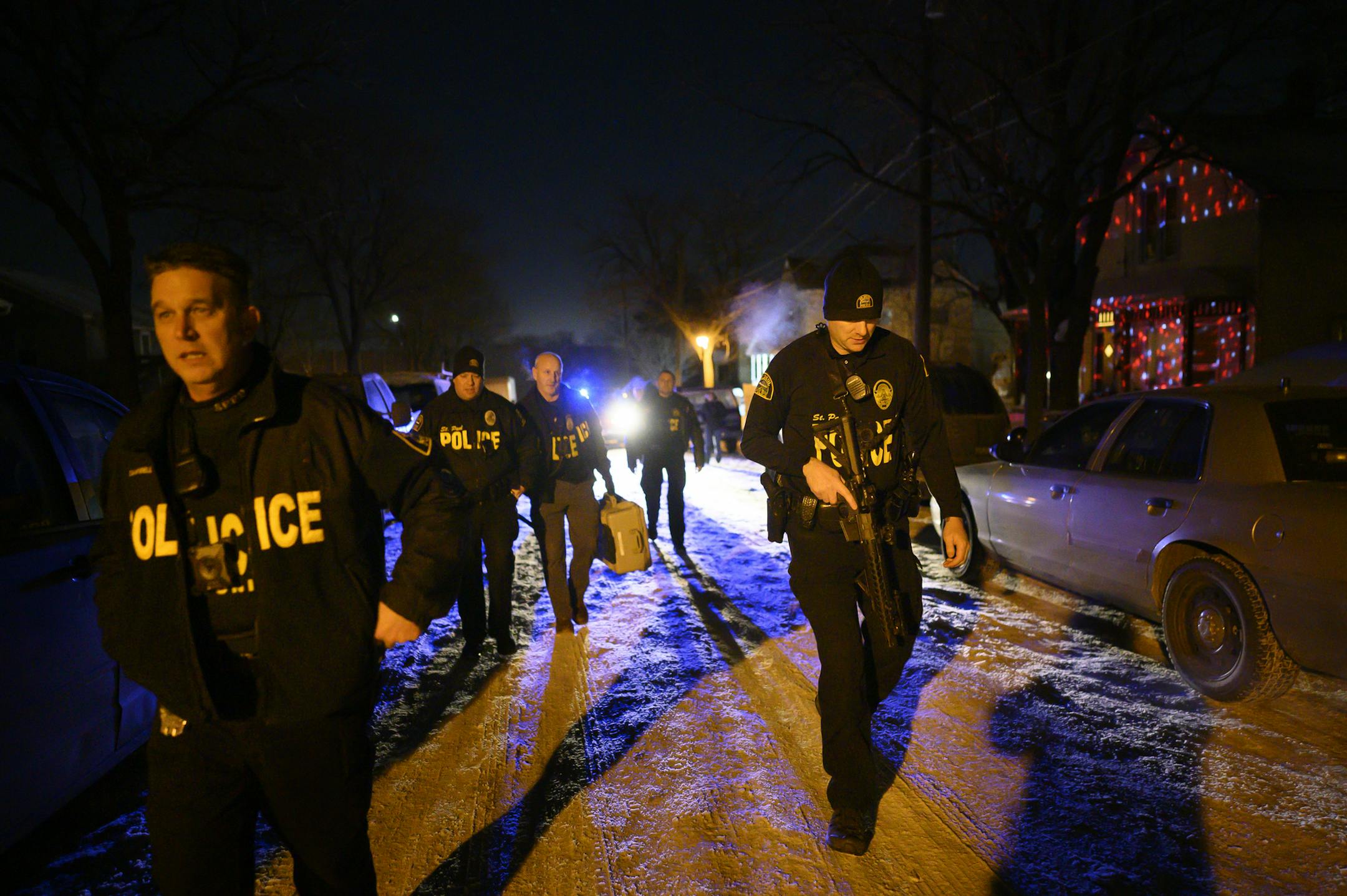 Members of the Saint Paul Police Department's gang unit, including Sgt. Shawn Campbell, left, and officer Colby Bragg, right, returned to their cars after executing a search warrant Wednesday night in the Central District which was related to a 2019 shooting.