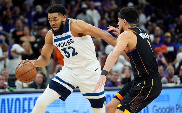 Karl-Anthony Towns drives on Suns guard Devin Booker during the first half of Game 3 in Phoenix.