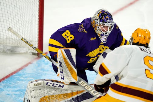 Minnesota State goaltender Dryden McKay, back, looks to stop a shot off the stick of Minnesota forward Sammy Walker in the third period of an NCAA College Hockey Regional Final, Sunday, March 28, 2021, in Loveland, Colo. (AP Photo/David Zalubowski)