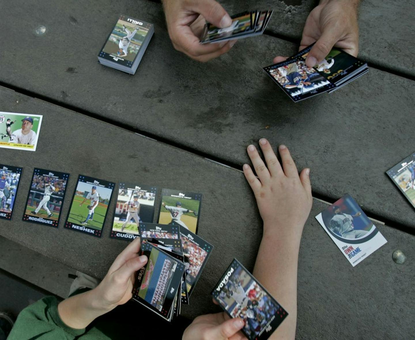 DAVID JOLES � djoles@startribune.com Fort Myers, FL - Feb. 25, 2007 - Minnesota Twins fans Todd Blackwell, from Fort Myers, FL, from top clockwise, and his twin sons Nickolas, 9, and Brantley, 9, sort through their baseball cards while waiting to get autographs during Twins spring training session Sunday at Lee County Sports Complex. "I want this guy," said Nickolas, pointing to a baseball card of Johan Santana.