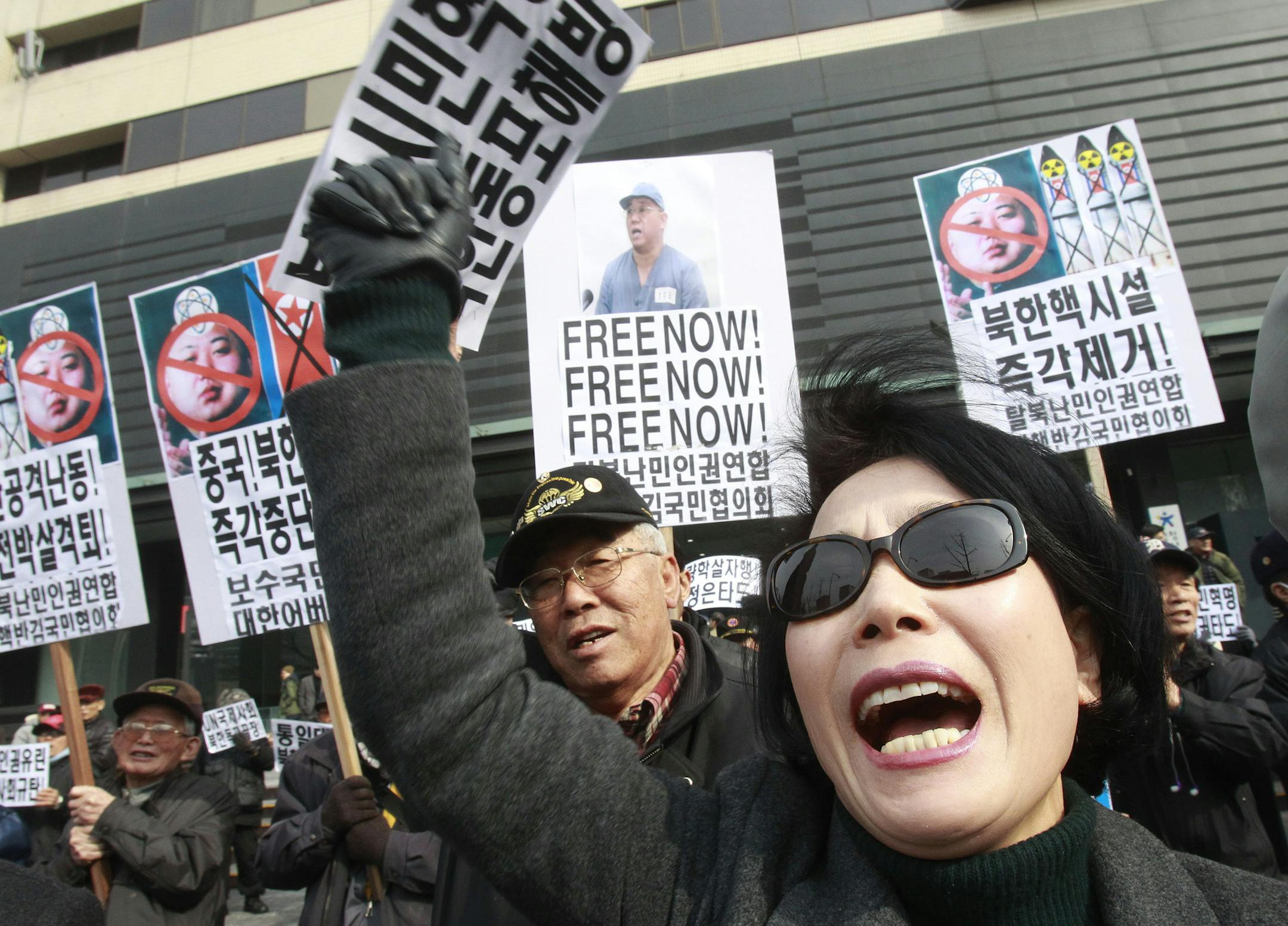 A protester shouts anti-North Korea slogans as others hold up placards of defaced photos of North leader Kim Jong Un during a rally in Seoul, South Korea, Sunday, Feb. 16, 2014. North Korea marked the anniversary of the birth of their late leader Kim Jong Il, on Sunday. The placards read: Immediately remove North Korea's nuclear facilities." (AP Photo/Ahn Young-joon)