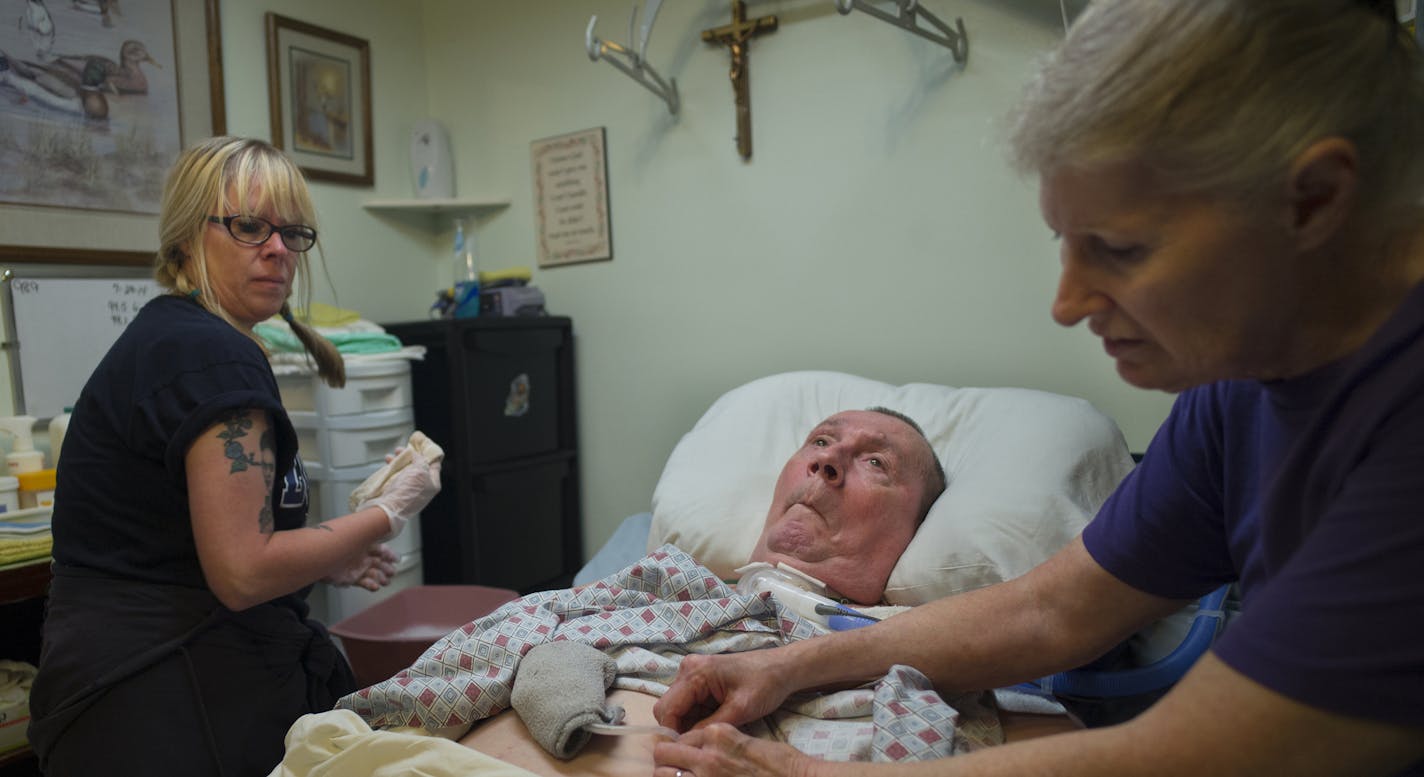 At the home of Linda Jarvis who living room has been turned into a hospital room for husband Gary Jarvis, who suffered a massive stroke and needs 24-hour care, PCA Teri Sernett works with Linda to help clean Gary's feeding tube. ] Richard Tsong-Taatarii/rtsong-taatarii@startribune.com