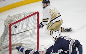 The puck goes over Rochester Century/John Marshall goalie Kyle Lappi (50) while Chanhassen's Caden Lee (24) watches. Lee recorded the assist — his s