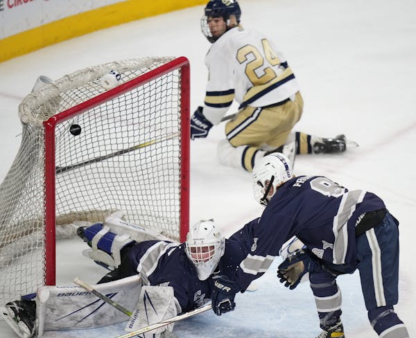 The puck goes over Rochester Century/John Marshall goalie Kyle Lappi (50) while Chanhassen's Caden Lee (24) watches. Lee recorded the assist — his s