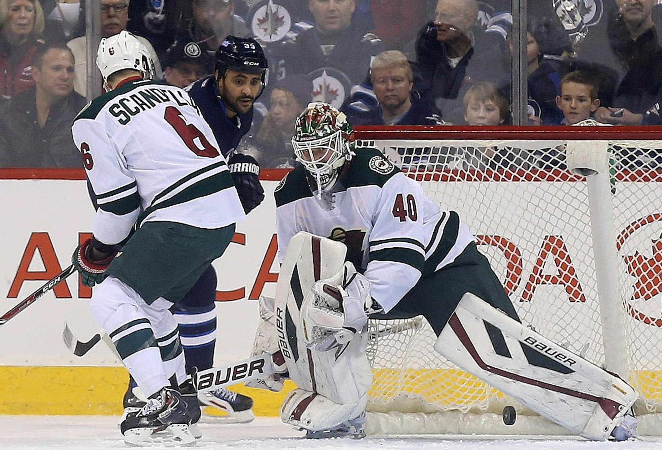 Winnipeg Jets' Dustin Byfuglien (33) tries a shot from a sharp angle but Minnesota Wild goaltender Devan Dubnyk (40) stops the puck with Marco Scandella (6) in front of the net during the first period of an NHL hockey game Tuesday, Feb. 10, 2015, in Winnipeg, Manitoba. (AP Photo/The Canadian Press, Trevor Hagan)