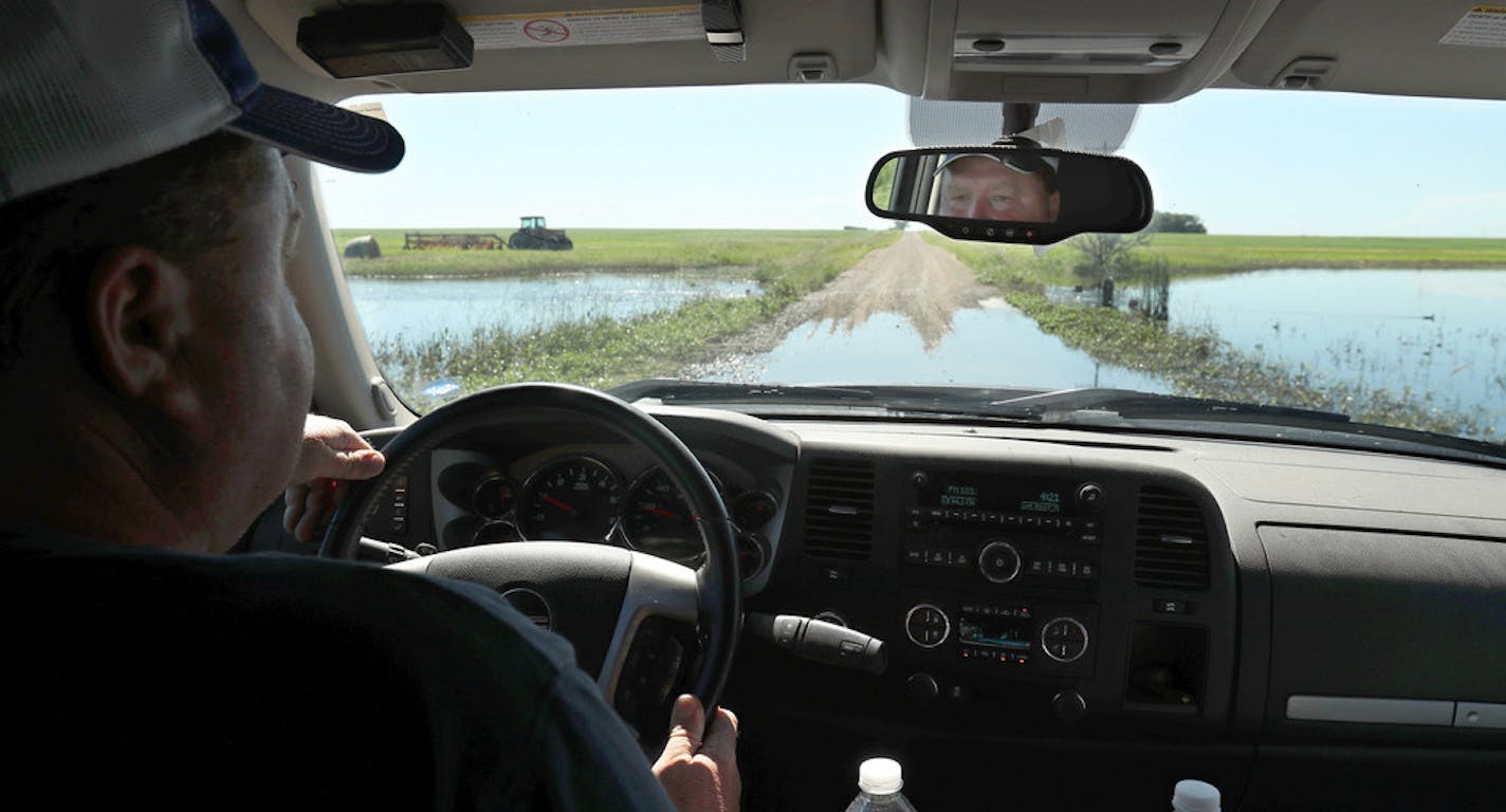 Tis photo taken July 2, 2019, shows Lannie Mielke driving through standing water on the road near his farm in Aberdeen, S.D. Mielke and other area farmers around Aberdeen are having problems with planting and day to day operations due to wet ground caused by spring runoff and rainfall, Mielke said nearly six inches of rain fell on some of his land at the end of June. (John Davis/Aberdeen American News via AP)