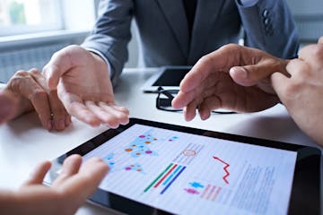 Three business people examining graphs on the screen of digital tablet. istock