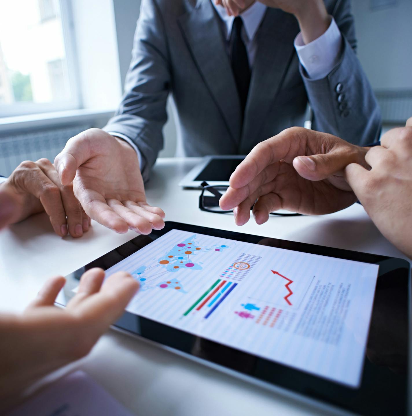 Three business people examining graphs on the screen of digital tablet. istock