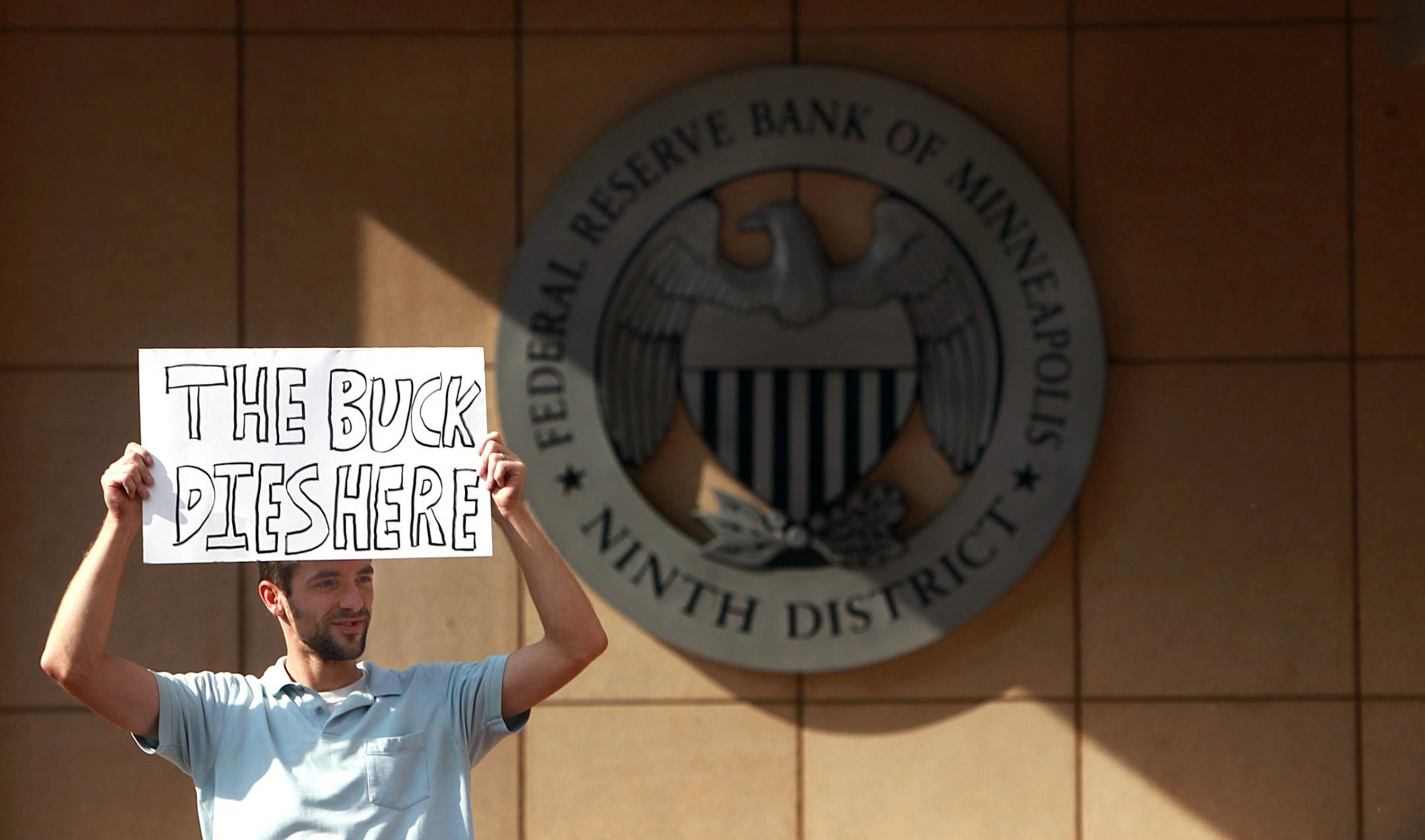 Alex Miller, Fridley, held up a sign as he and dozens of other protesters descended upon the Federal Reserve Bank of Minneapolis.