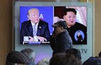 A man passes by a TV screen showing file footage of U.S. President Donald Trump, left, and North Korean leader Kim Jong Un during a news program at th