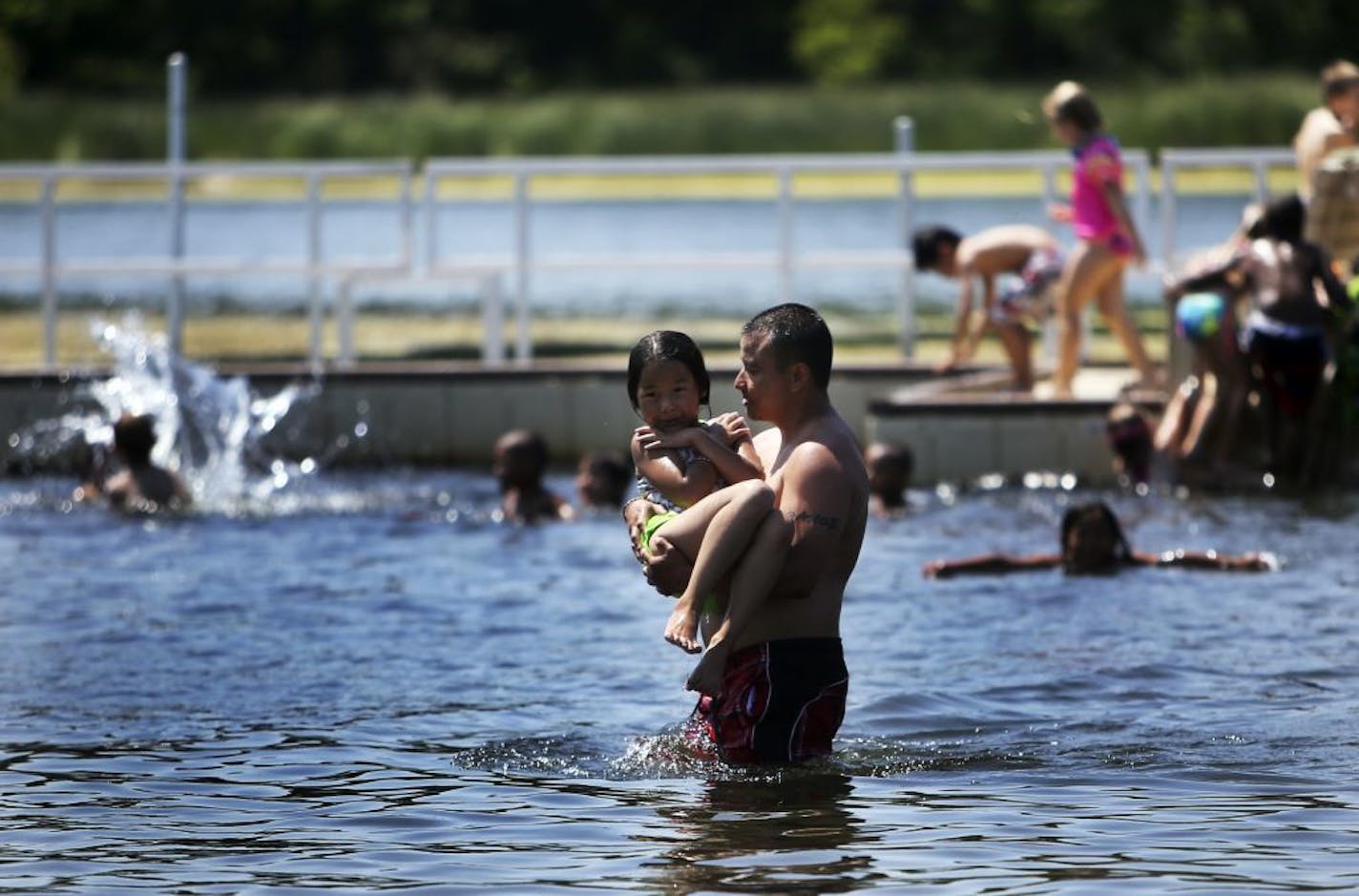 Lee Song, 37, of Minneapolis, carries his daughter Jocelyn, 7, to shore after swimming in Wirth Lake in Theodore Wirth Park Tuesday, July 2, 2013, in Minneapolis, MN. Song was chaperoning a total of seven children at the beach.