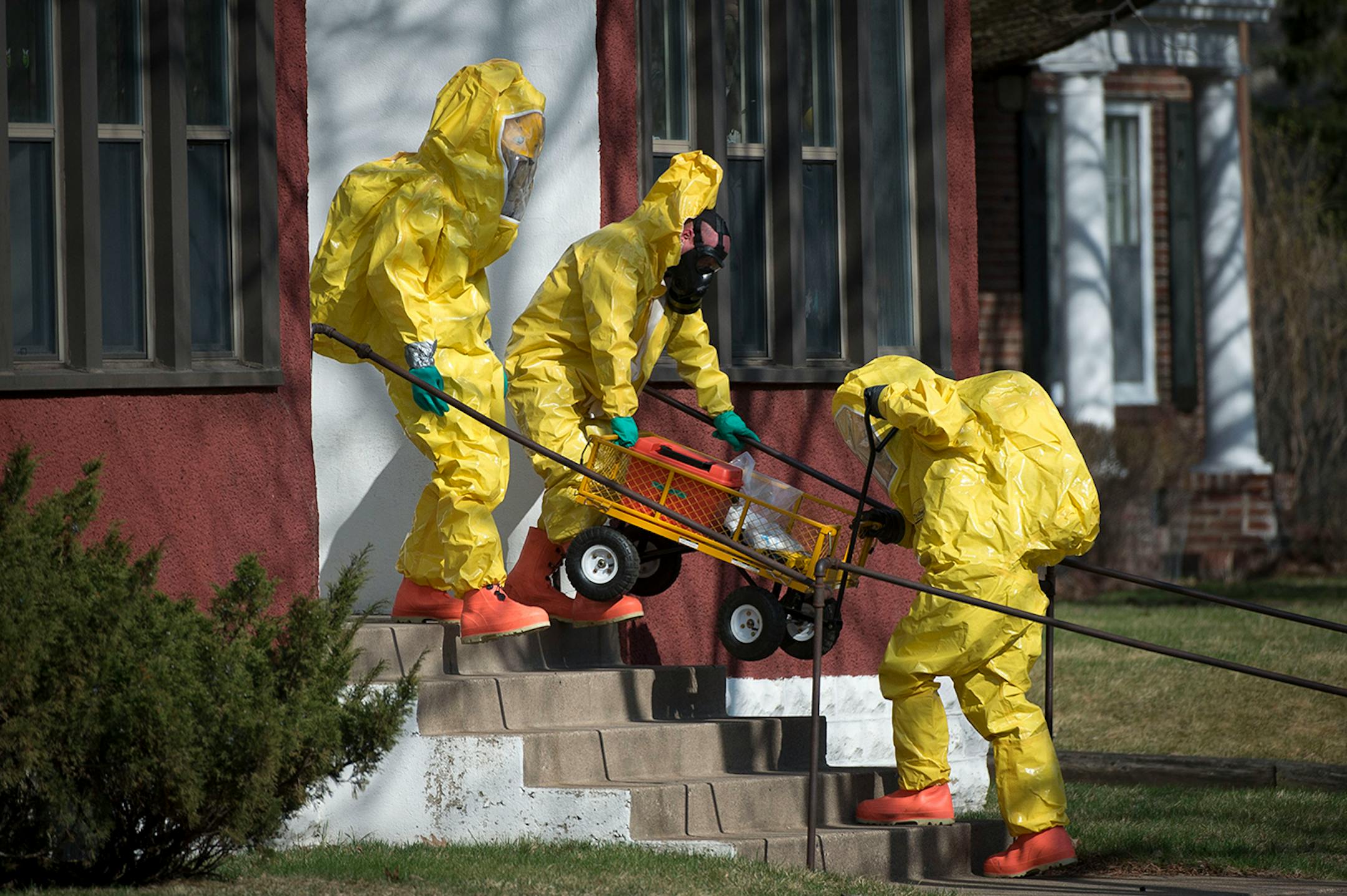 Hazardous material workers carry out their gear while leaving a residence in the Marcy Holmes neighborhood of Minneapolis on the 500 block of 6th Street Southeast on Friday, April 10, 2015.