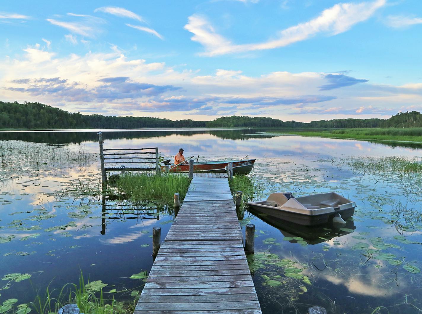 Dallas Hudson awaits in his small boat the beginning of an evening's crappie fishing on a picturesque northern Minnesota lake.