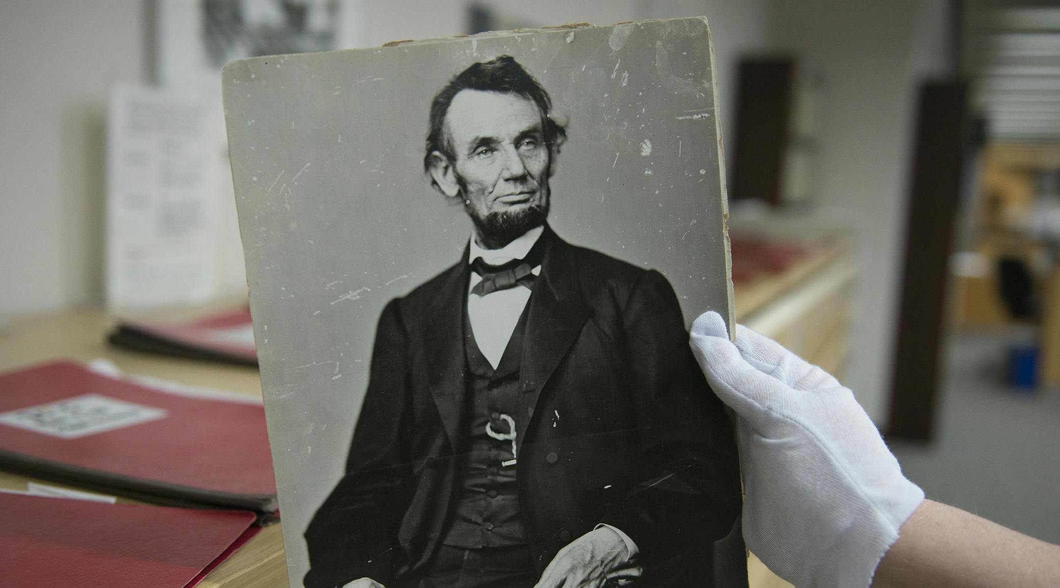 In this Monday, April 6, 2015 photo, Karen Needles holds up a photograph of President Abraham Lincoln at the National Archives in College Park, Md. Three blocks away, 150 years earlier, Lincoln was felled by an assassin's bullet. (AP Photo/Molly Riley) ORG XMIT: MIN2015042317394163