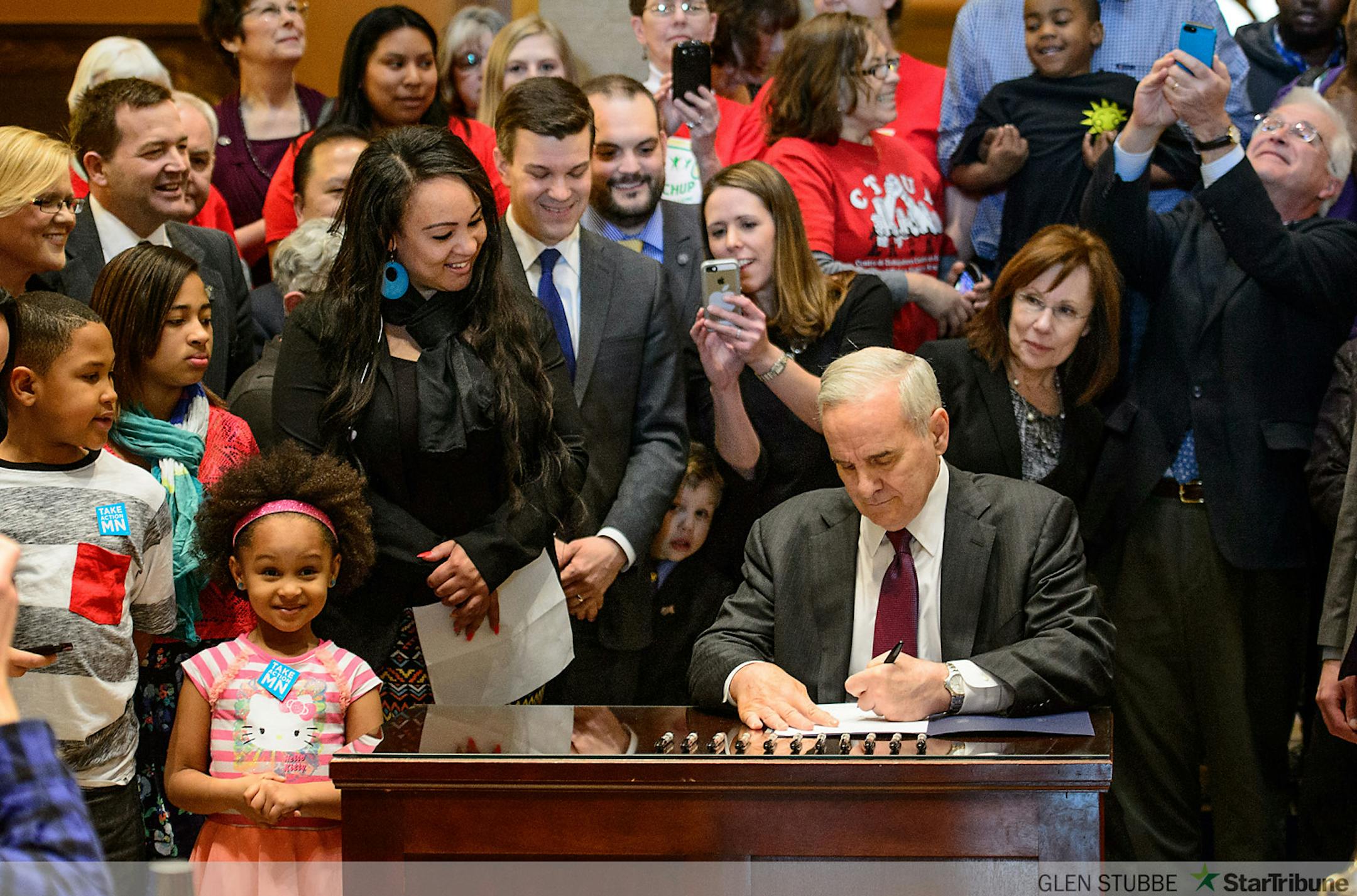 Surrounded by lawmakers and advocates for the bill, Governor Mark Dayton signed the minimum wage bill into law at a public bill signing ceremony Monday the Minnesota State Capitol Rotunda.  The bill, which was passed by the Legislature last week, will increase Minnesota's minimum wage to $9.50 per hour, and index it to inflation.       ]   GLEN STUBBE * gstubbe@startribune.com   Monday, April 14, 2014