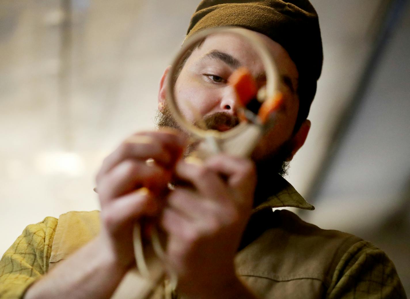 Maxwell Kelsey's reverence for tradition and attention to detail have turned him into one of the region's go-to makers of old-style, wooden lacrosse sticks. At top, he used a piece of ash that he split from a log and a draw knife to shape the wood into a lacrosse stick. Above left, he strung the netting he had made earlier from twisted wood fibers.