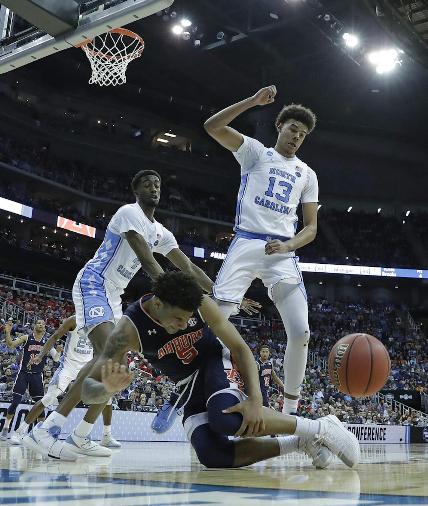 Auburn's Chuma Okeke (5) grabs his leg as he loses control of the ball on his way to the basket as North Carolina's Cameron Johnson (13) and North Carolina's Brandon Robinson, left, defend during the second half of a men's NCAA tournament college basketball Midwest Regional semifinal game Friday, March 29, 2019, in Kansas City, Mo. Okeke was injured on the play. (AP Photo/Charlie Riedel)