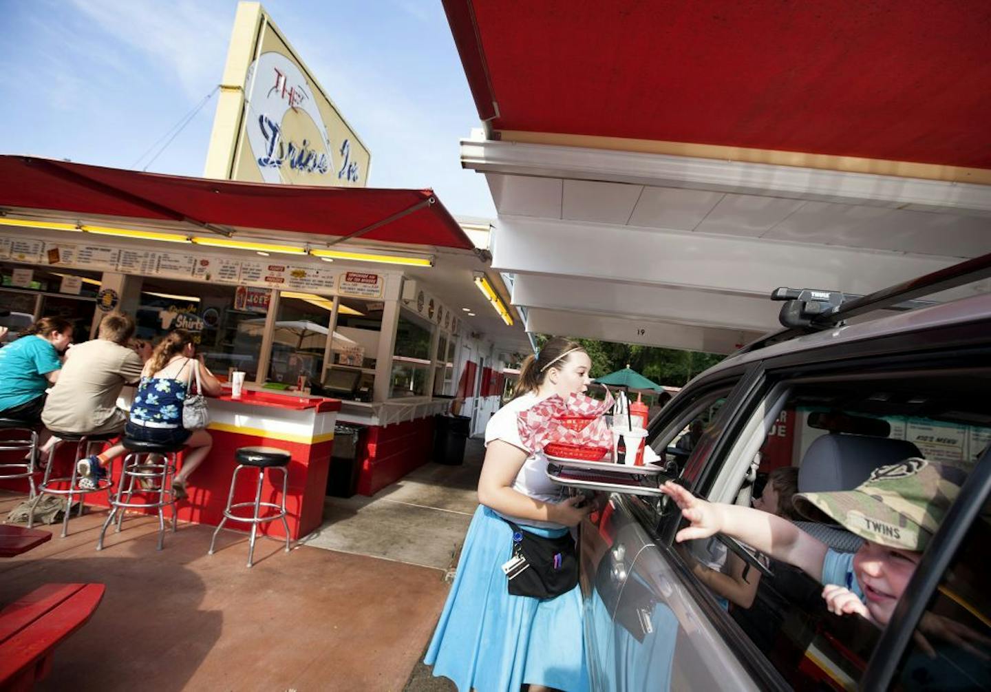 Lola Smestad, 16 months, reaches out from her car window as carhop Beth Peterson checks in for a dessert order at The Drive-In in Taylors Falls, June 26, 2014.