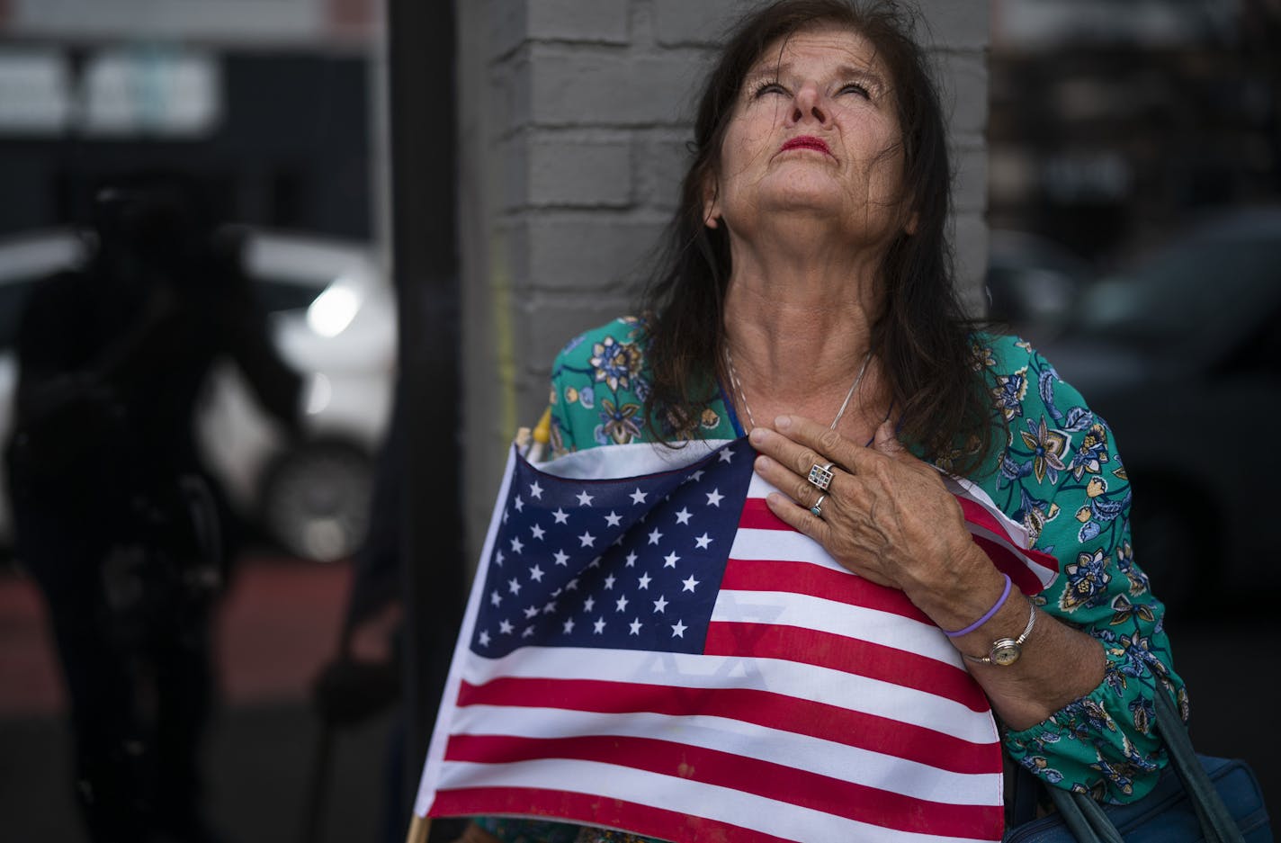 Merrilyn Downs clinched the U.S. flag as she prayed at the site where a shooting happened early Sunday Morning in the 2900 block of Hennepin Avenue south.] Jerry Holt •Jerry.Holt@startribune.com Gunmen unleashed a torrent of gunfire in a crowded Uptown block early Sunday in Minneapolis, killing one person and wounding 11 others in one of the city's most violent shootings in recent memory. Sunday ,June 21, 2020 in Minneapolis ,MN.