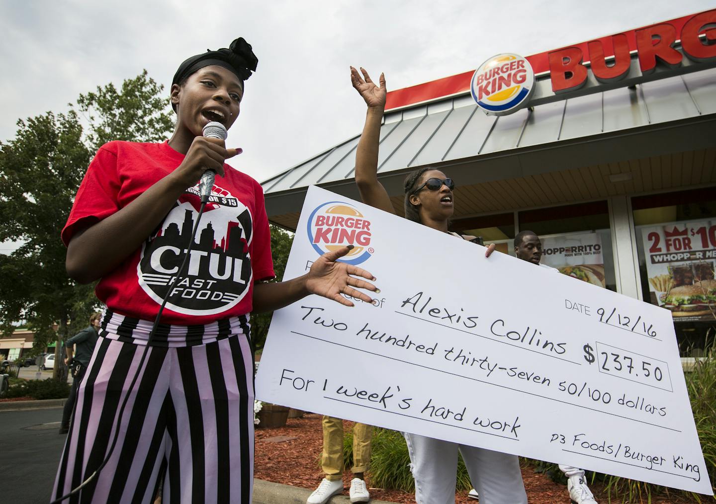 Alexis Collins, a worker at Burger King, speaks about her low wages while displaying what her weekly check looks like outside of a Burger King during a rally and march down W. Broadway Avenue. ] (Leila Navidi/Star Tribune) leila.navidi@startribune.com BACKGROUND INFORMATION: Activists supporting a $15 minimum wage rally and march outside corporate fast food restaurants, payday lenders and a bank on W. Broadway Avenue in north Minneapolis on Monday, September 12, 2016. The activists are pushing f