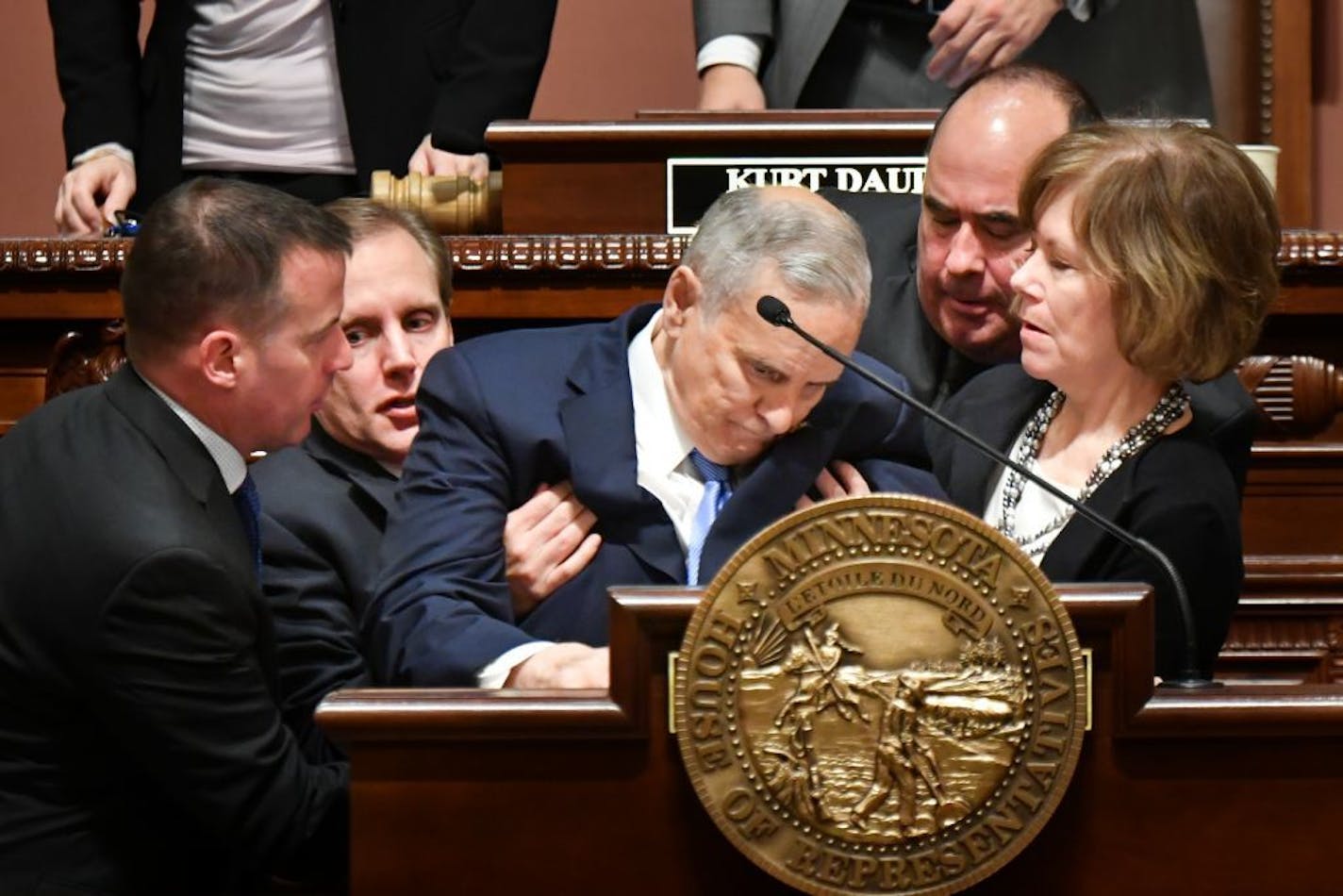 :Gov. Mark Dayton collapsed near the end of his annual State of the State speech Monday night as bystanders rushed to help. They included state Sen. Matt Klein, far left, who is a doctor, Secretary of State Scott Simon at Dayton's right and Lt. Gov. Tina Smith on his left.