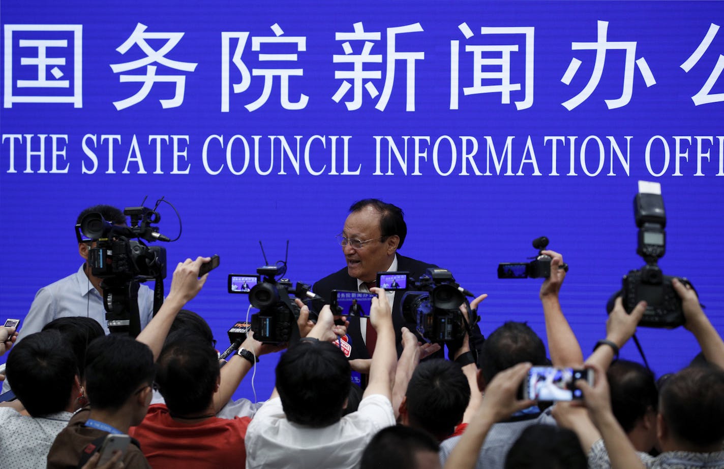 Shohrat Zakir, center, chairman of China's Xinjiang Uighur Autonomous Region, speaks as he is approached by journalists after a press conference at the State Council Information Office in Beijing, Tuesday, July 30, 2019. The governor of China's far-northwestern region of Xinjiang is defending controversial re-education centers in the region as an effective deterrent against terrorism and religious extremism. (AP Photo/Andy Wong)