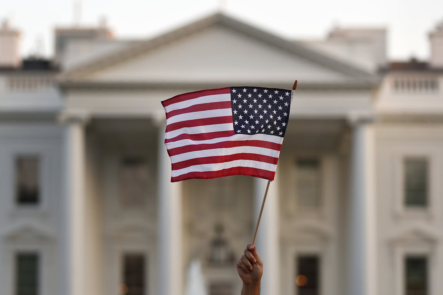 FILE - In this Sept. 2017 file photo, a flag is waved outside the White House, in Washington. The Trump administration announced Friday that it was curbing legal immigration from six additional countries that officials said did not meet security screening standards, as part of an election-year push to further restrict immigration. Officials said immigrants from Kyrgyzstan, Myanmar, Eritrea, Nigeria, Sudan and Tanzania will face new restrictions in obtaining certain visas to come to the United St