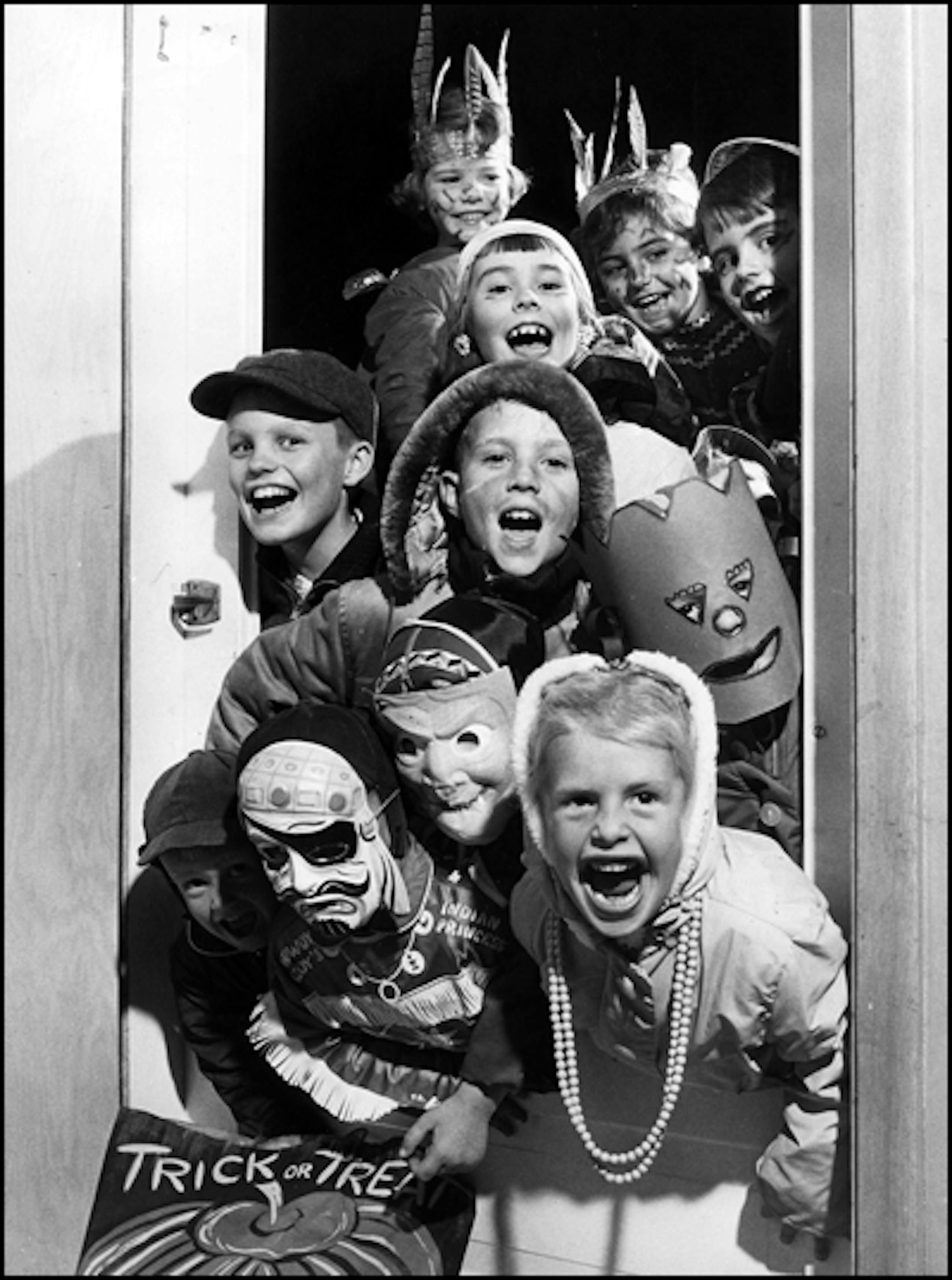 Original caption: Where's the treats? Eleven trick-and-treaters prowling St. Louis Park for goodies Thursday night literally tumbled into the home of Minneapolis Tribune photographer Earl Seubert. Seubert, a regular goblin with camera and strobe, didn't seem to frighten the young Indians and pirates when he "shot" them arriving at 2413 Xylon Avenue. Incidentally, the neighborhood children didn't crash through glass to stick their heds and treat sacks into the entrance hall -- Seubert hasn't put