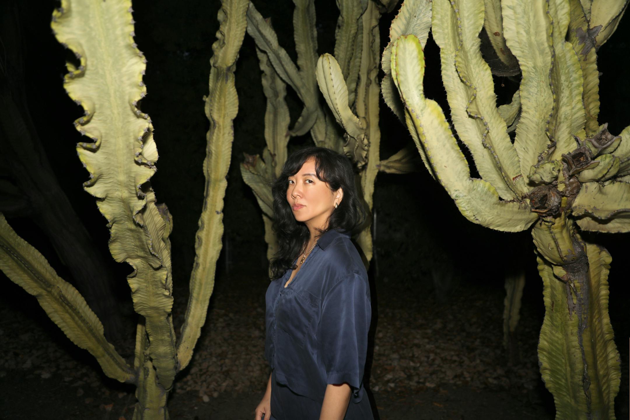 author Jade Chang is photographed at night in the midst of a bunch of gnarly cacti
