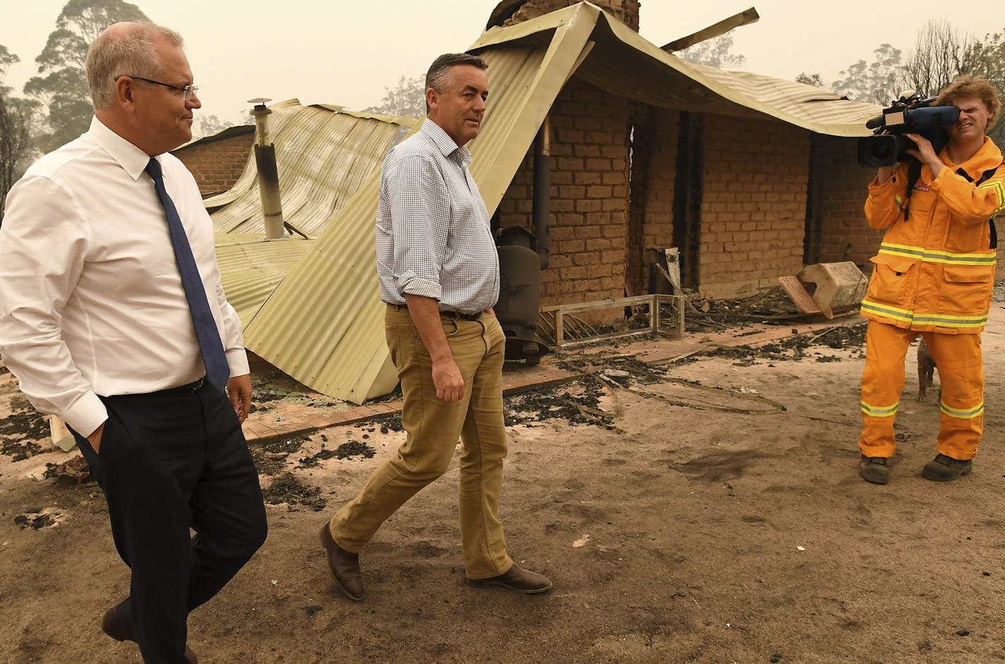 Australian Prime Minister Scott Morrison, front left, and Darren Chester MP tour the Wildflower farm owned by Paul and Melissa Churchman in Sarsfield, Victoria, Friday, Jan. 3, 2020. Navy ships plucked hundreds of people from beaches and tens of thousands were urged to flee Friday before hot weather and strong winds in the forecast worsen Australia's already-devastating wildfires. (James Ross/Pool Photo via AP)