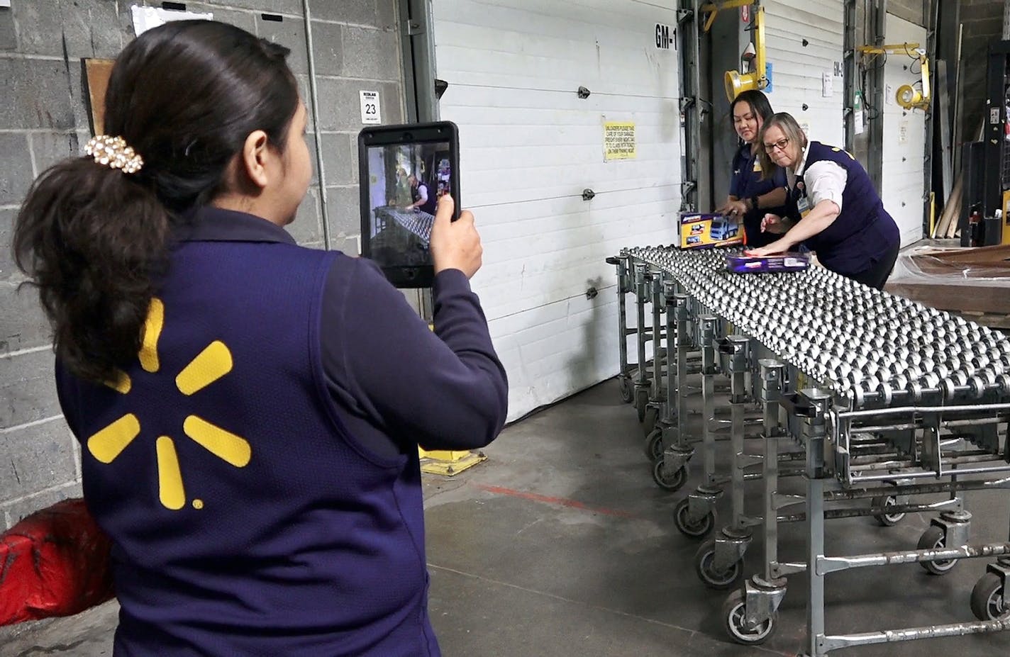 Wal-Mart Academy students Celia Flores Lagunas, from left, Cherie Johnson and Janet Holcomb make a short video showing the product cycle at a typical Wal-Mart, including unloading new merchandise. (Keith Myers/Kansas City Star/TNS)