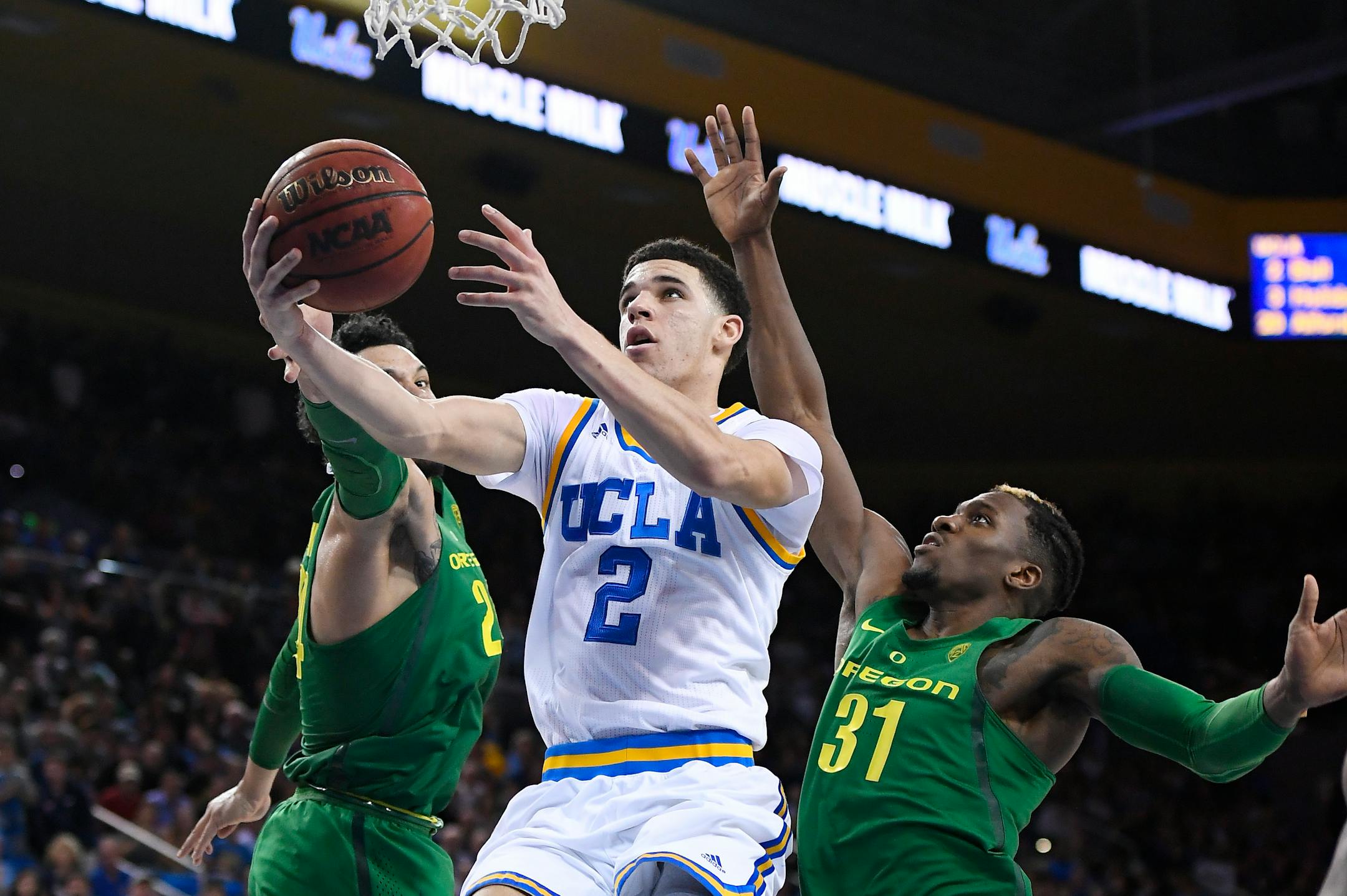 UCLA guard Lonzo Ball, center, shoots as Oregon forward Dillon Brooks, left, and guard Dylan Ennis defend during the second half of an NCAA college basketball game, Thursday, Feb. 9, 2017, in Los Angeles. UCLA won 82-79. (AP Photo/Mark J. Terrill)