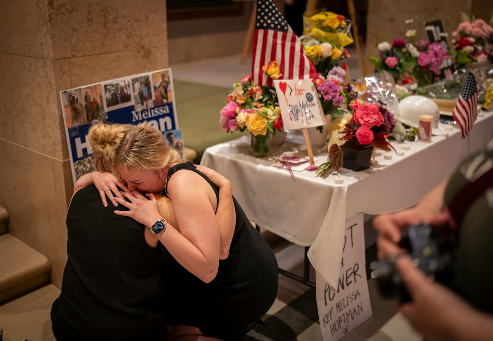 Loved ones, who declined to give their names, of Minnesota House Democratic leader Melissa Hortman and her husband Mark Hortman embraced after hanging a sign with pictures of the couple and their dog Gilbert at a memorial outside the House Chambers at the Minnesota State Capitol on Monday. The Hortmans were fatally shot in their Brooklyn Park home on Saturday morning. Their dog Gilbert was recently put down due to injuries from the shooting.