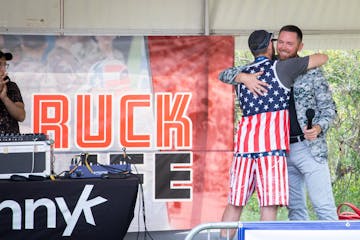 Mike Waldron hugs a man in a stars and stripes outfit while standing on a stage.