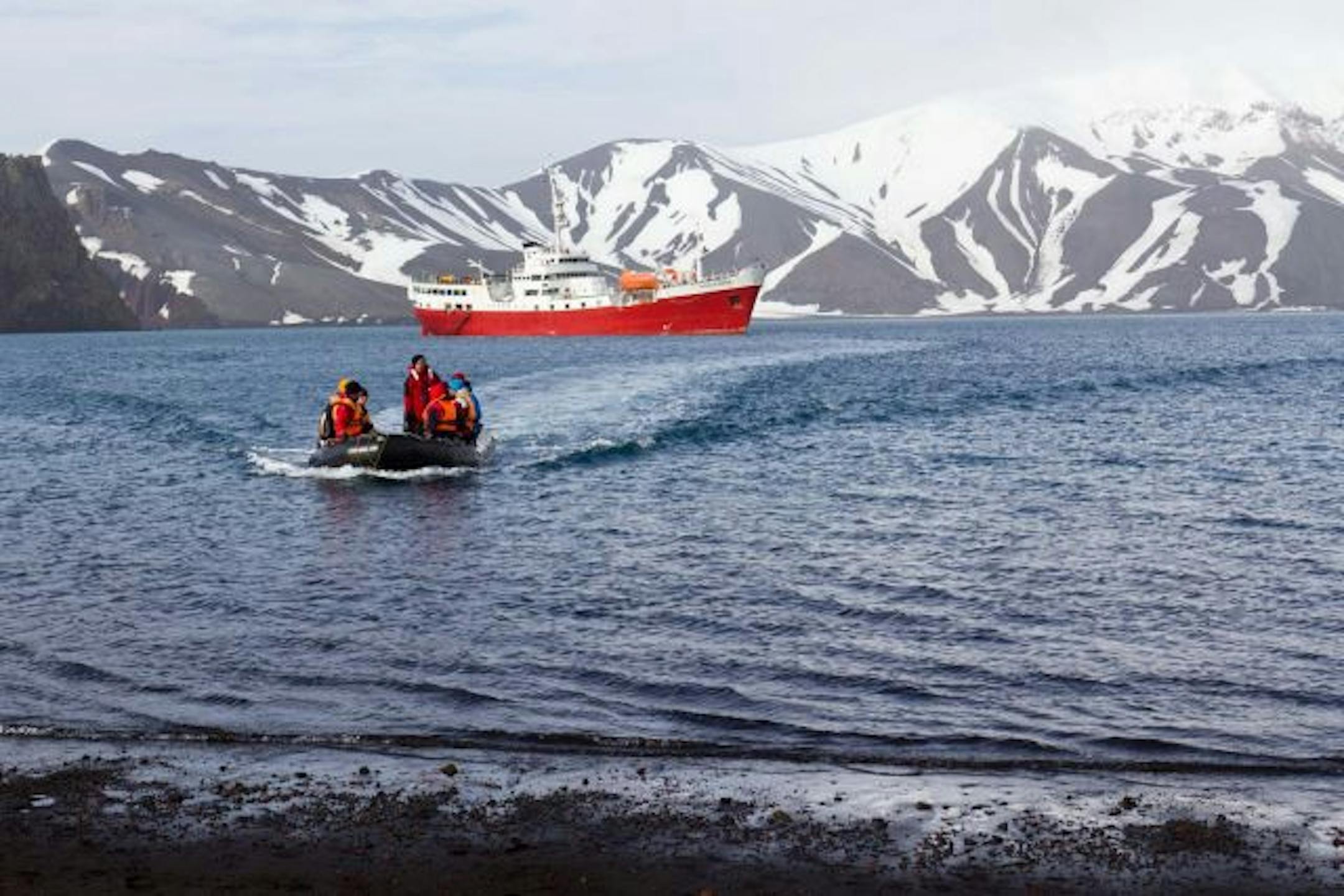 ] Zodiacs filled with passengers from the M/V Antarctic Dream approach Antarctica shoreline.