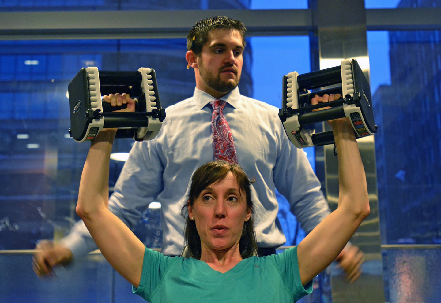 Julie Ennis pressed PowerBlocks as part of her early morning workout. Watching her progress is personal trainer/strength coach Brandon Jonker, general manager of the Discover Strength downtown Minneapolis location. ] Joey McLeister,Special to the Star Tribune,Minneapolis,MN December11,2012