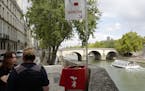 A municipal employee, right, talks to a person next to an urinal installed on the Seine river banks on the Ile de la Cite, Tuesday, Aug.14, 2018 in Pa